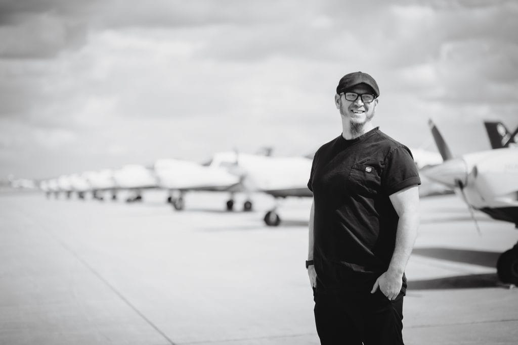 Josh Tuinder, REALTOR® with Oxford Realty in Grand Forks, North Dakota, standing on the UND Aerospace flight line