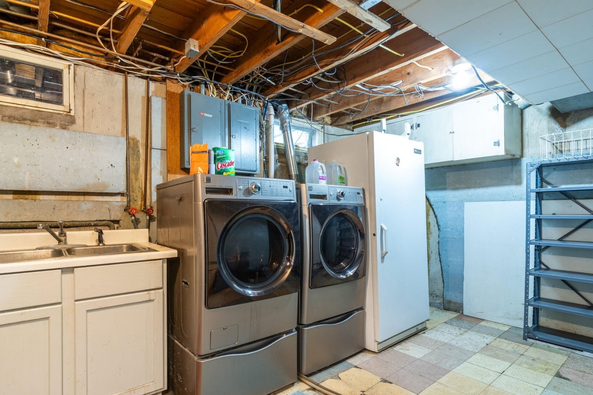 Unfinished basement laundry room with a front-load washer and dryer under an open ceiling