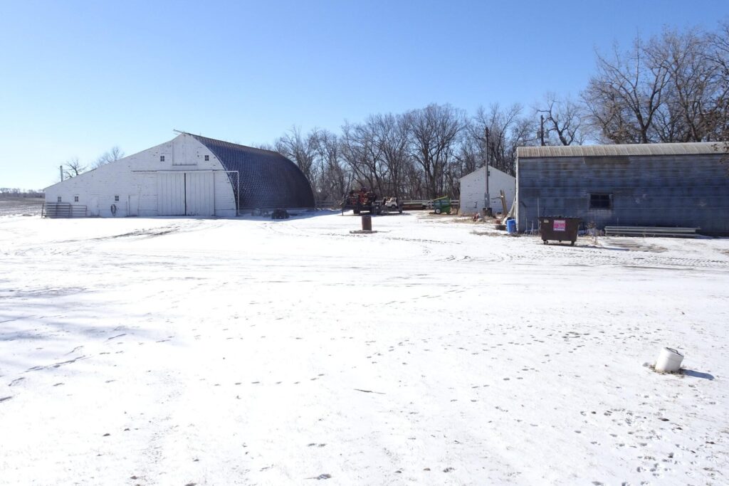 White arched barn, a shed and a metal Quonset building on a snow-covered farmyard near Niagara, ND