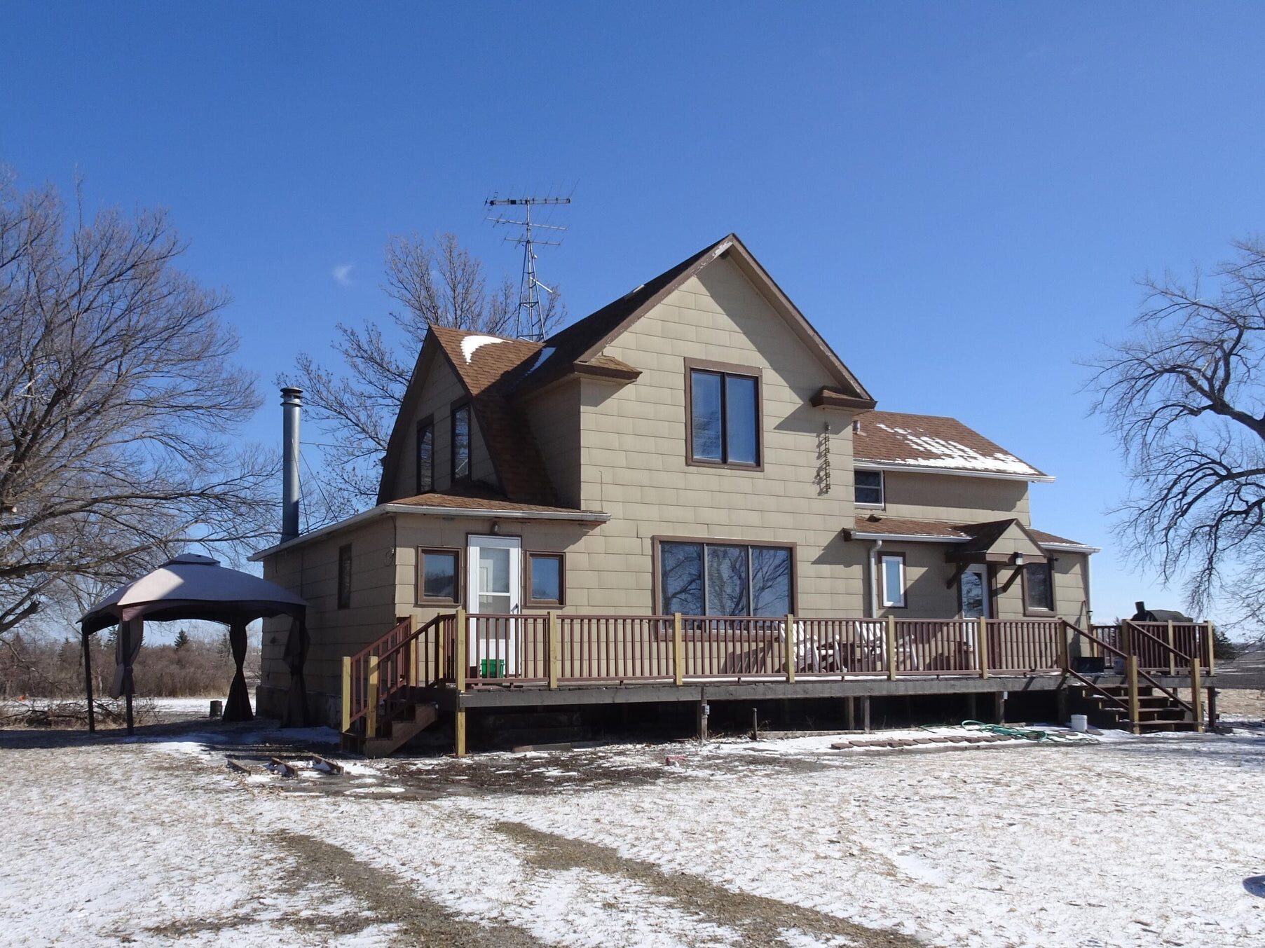 Two-story house with a long wooden deck and a gazebo on an acreage near Niagara, ND